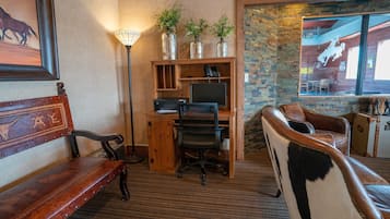 Um espaço de escritório acolhedor com uma mesa, cadeira e um banco. Há plantas em vasos sobre a mesa e uma moldura na parede.