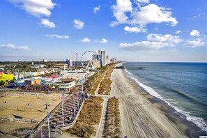 A coastal cityscape with a beach, a Ferris wheel, and a pier.
