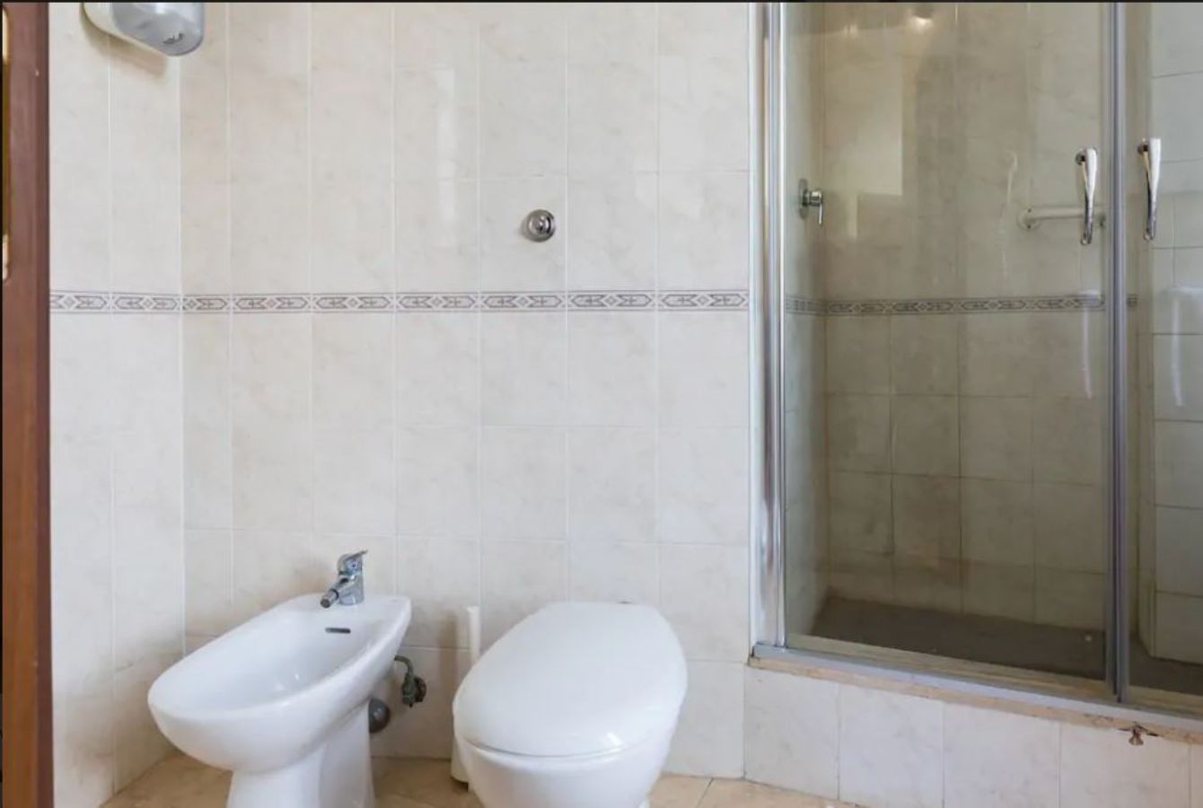 Une salle de bain équipée d’un bidet, de toilettes et d’une douche à parois de verre.