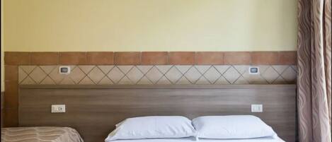 A hotel room with a bed, two bedside tables, and a headboard with a geometric pattern.