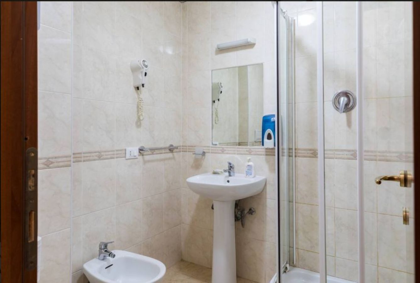A bathroom with a sink, mirror, and shower.