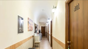 A hotel hallway with a wooden door marked "401", a bench, and a trash bin. - Alex Romano (Rome)