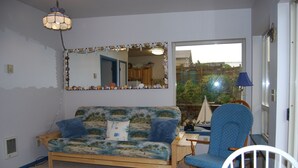 Una sala de estar con sofá, sillón, mesa, lámpara y un espejo grande.