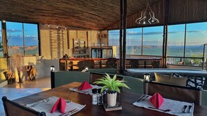 A restaurant with a bar, large windows, and a view of the landscape. - Ugab Terrace Lodge (Khorixas)