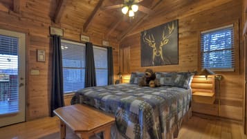 A wooden cabin bedroom with a bed, a bench, a ceiling fan, and a deer painting on the wall.