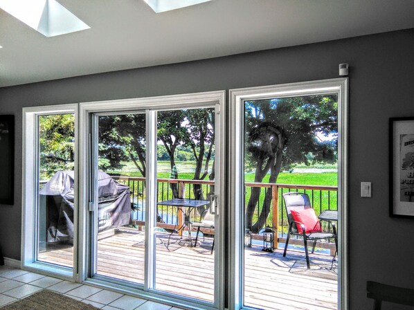 A room with a large sliding glass door leading to an outdoor deck with a table and chairs.