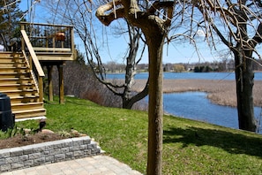 A wooden deck with a basketball hoop, a stone pathway, and a view of a lake.