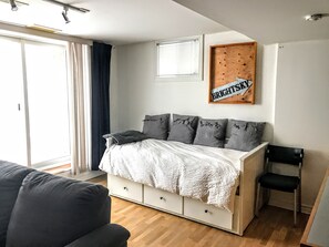 Quarto com cama, uma cadeira, janela e um letreiro fixado na parede.