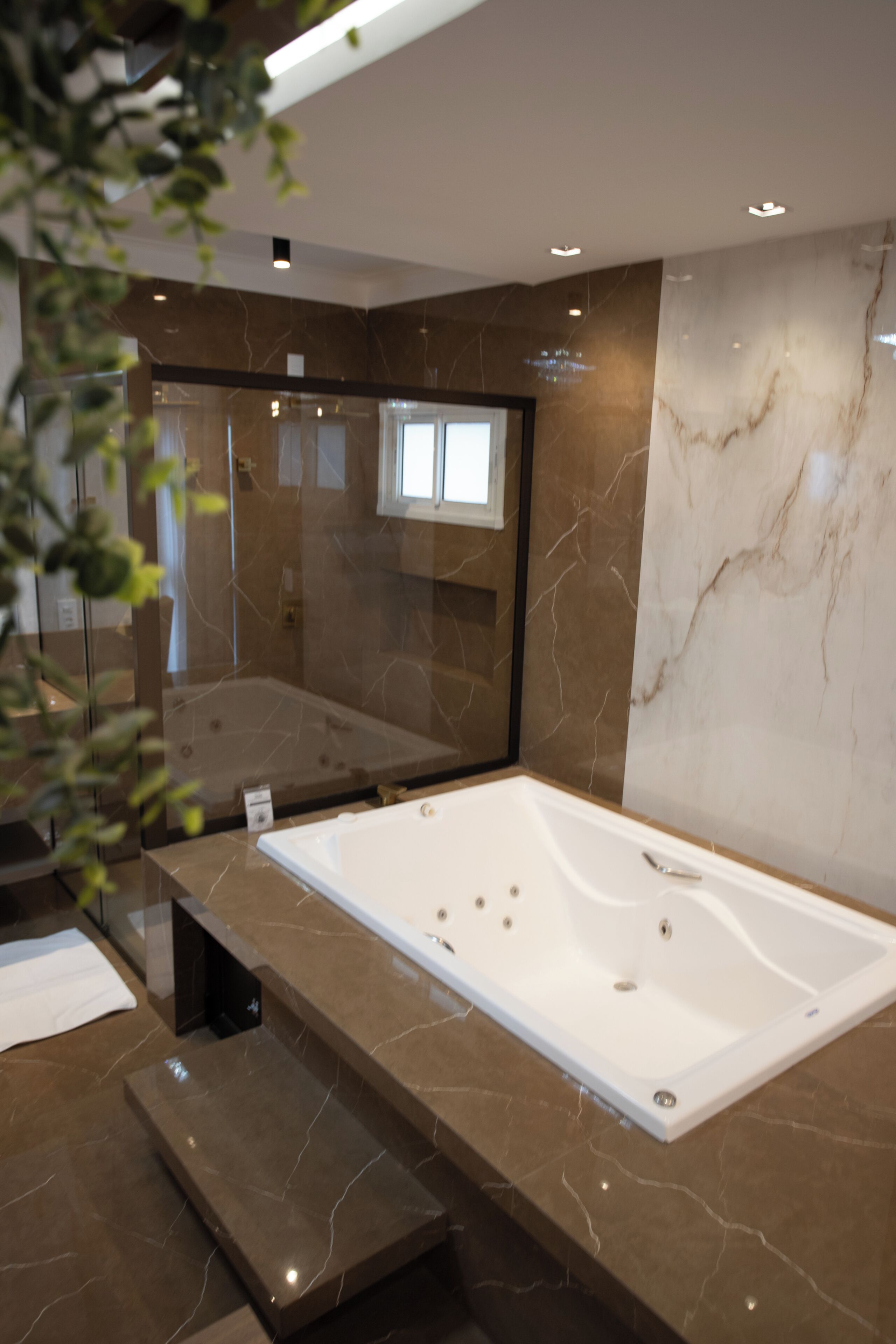 Un baño moderno con una bañera grande, paredes de mármol y una cabina de ducha de vidrio.