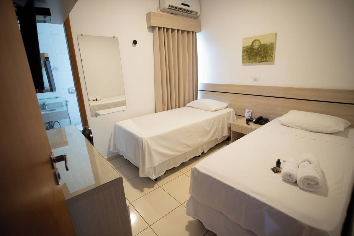 A hotel room with two beds, a bathroom, and a small desk.