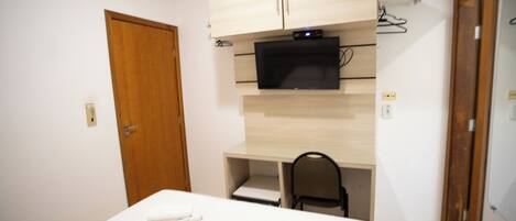 A bedroom with a bed, a desk with a chair, a television, and a wardrobe.