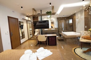 Una habitación de hotel moderna con una cama grande, un escritorio, un televisor, un baño con bañera y ducha.