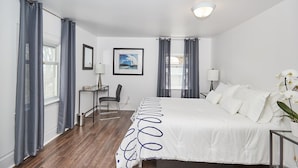 Une chambre d’hôtel avec un grand lit, un bureau avec une chaise, une petite table et une plante en pot.