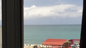 A view of the sea from a window with a red-roofed structure in the foreground. - Beautiful Condo -Ocean View, Best Location, Pool, Parking & Steps to All U Want (San Juan)