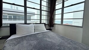 A hotel room with a large bed, a window with curtains, and a view of buildings and the sea. - Beautiful Condo -Ocean View, Best Location, Pool, Parking & Steps to All U Want (San Juan)