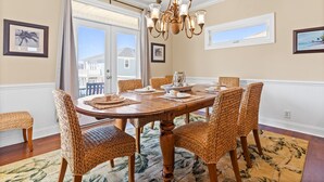 Une salle à manger avec une table en bois, des chaises en osier et un lustre.