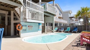 Un espace piscine doté d’un poste de surveillance pour les sauveteurs, de chaises longues et d’une terrasse en bois.