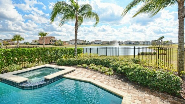 A swimming pool with a hot tub, surrounded by palm trees and a fence, with houses in the background. - Reunion 5 Bedroom Vacation Home 7824 (Kissimmee)
