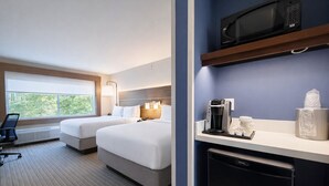Habitación de hotel con dos camas, un escritorio, una computadora, un microondas, una cafetera y un cubo de basura.