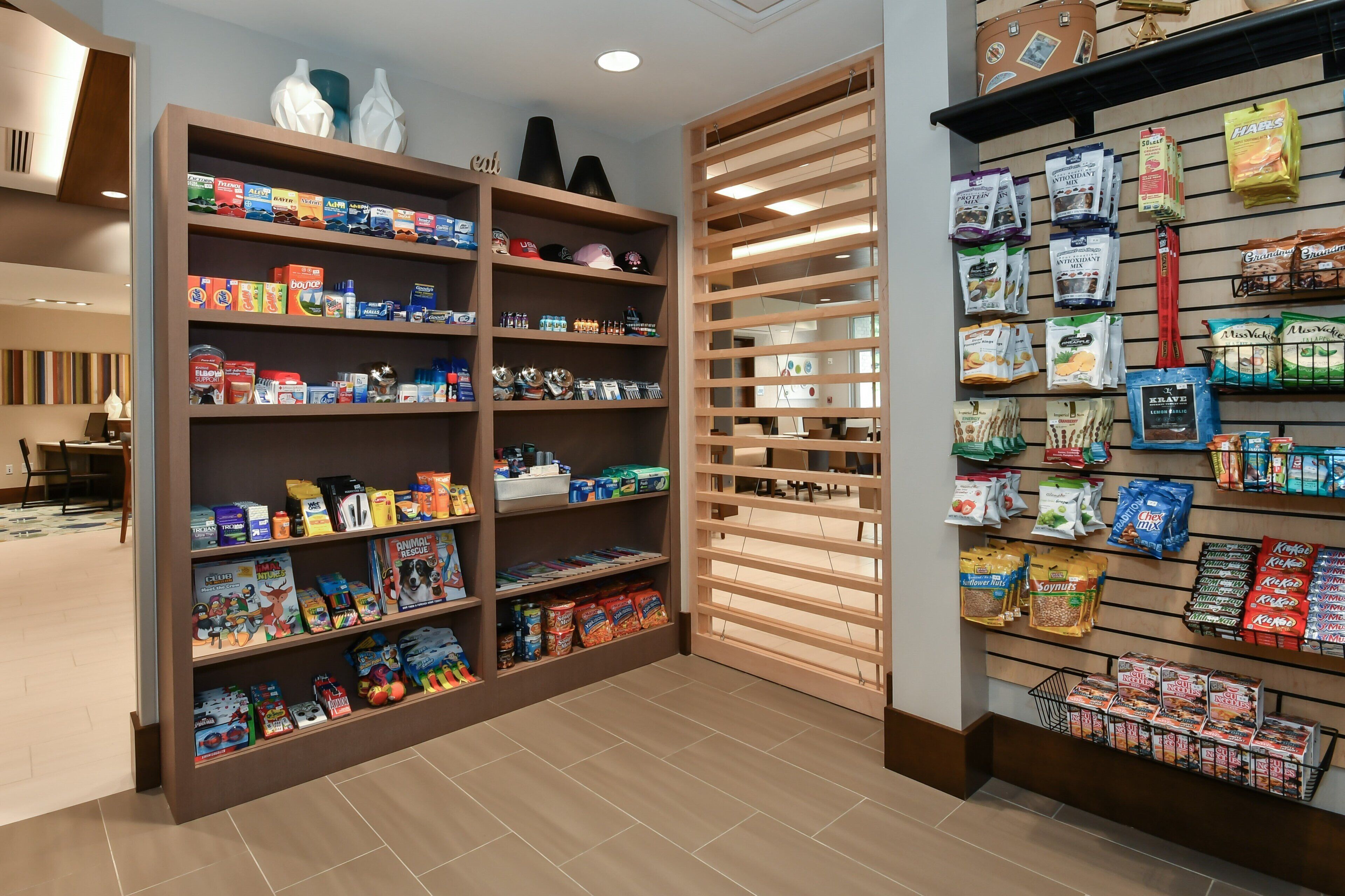 Un espacio comercial bien organizado con estantes llenos de diversos productos, como aperitivos, bebidas y artículos para el hogar.