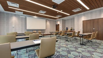 Une salle de conférence équipée d’un grand écran, de plusieurs tables et de chaises.