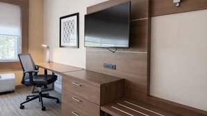 Un espacio de oficina moderno con un escritorio de madera, una silla de oficina negra, un televisor de pantalla plana montado en la pared y un cuadro enmarcado sobre el escritorio.