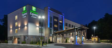 A Holiday Inn Express & Suites hotel with a modern design, featuring a covered entrance and a parking lot.