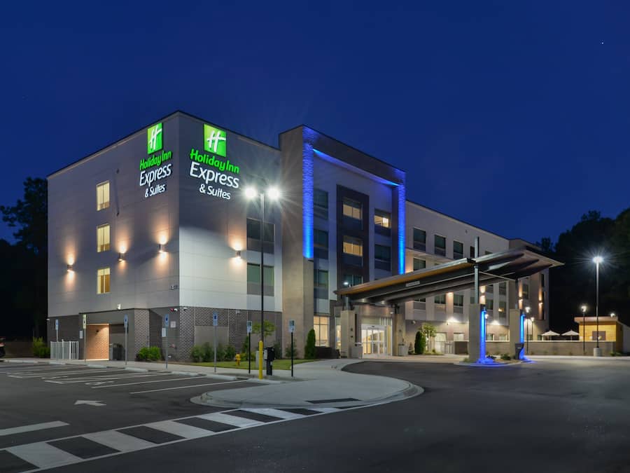 Un hotel Holiday Inn Express & Suites con diseño moderno, que cuenta con una entrada cubierta y un estacionamiento.