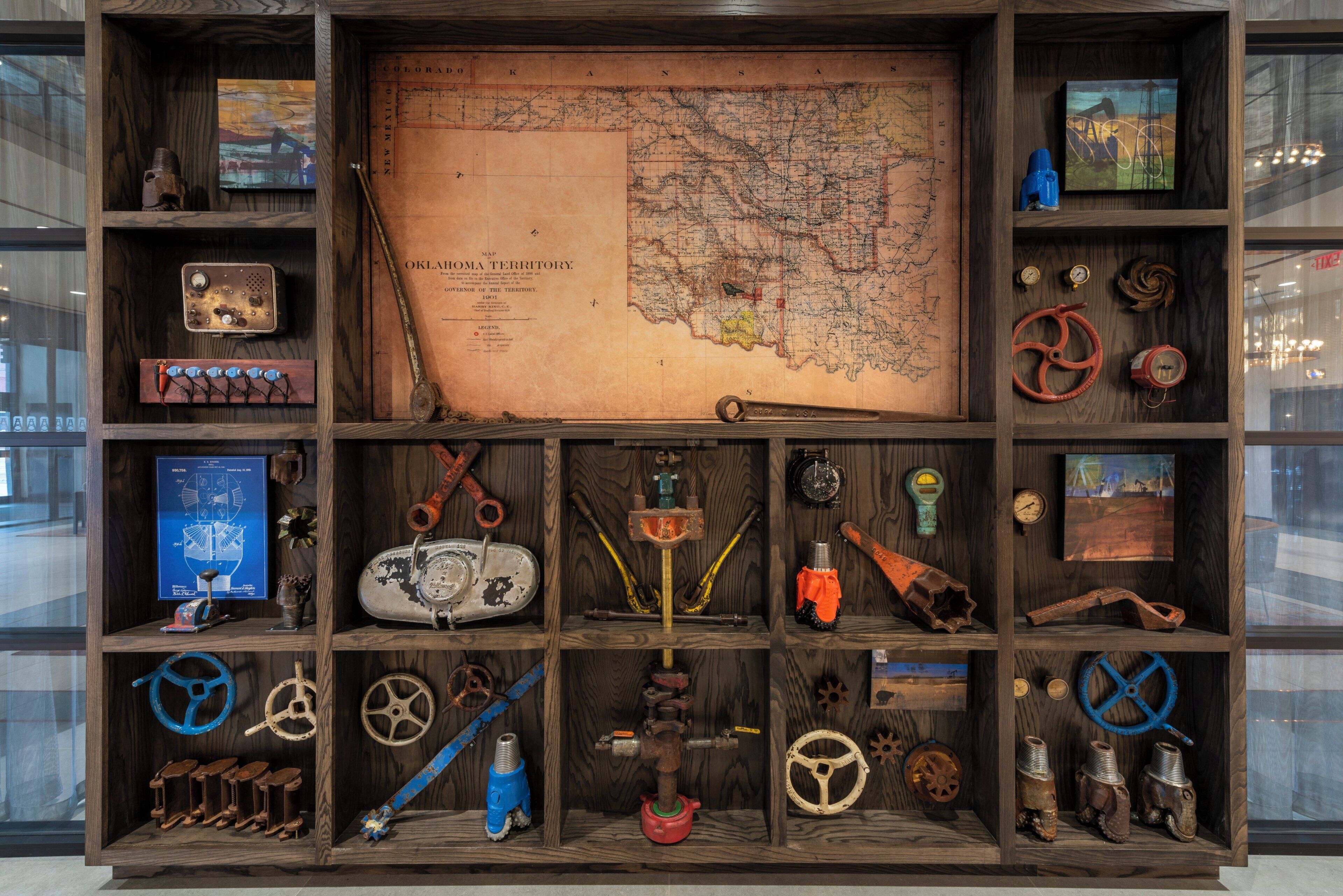 A wooden display case with a map of Oklahoma Territory, vintage tools, and mechanical parts.