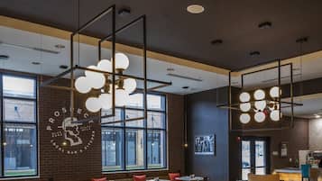 A modern restaurant interior with high ceilings, exposed brick walls, and large windows.