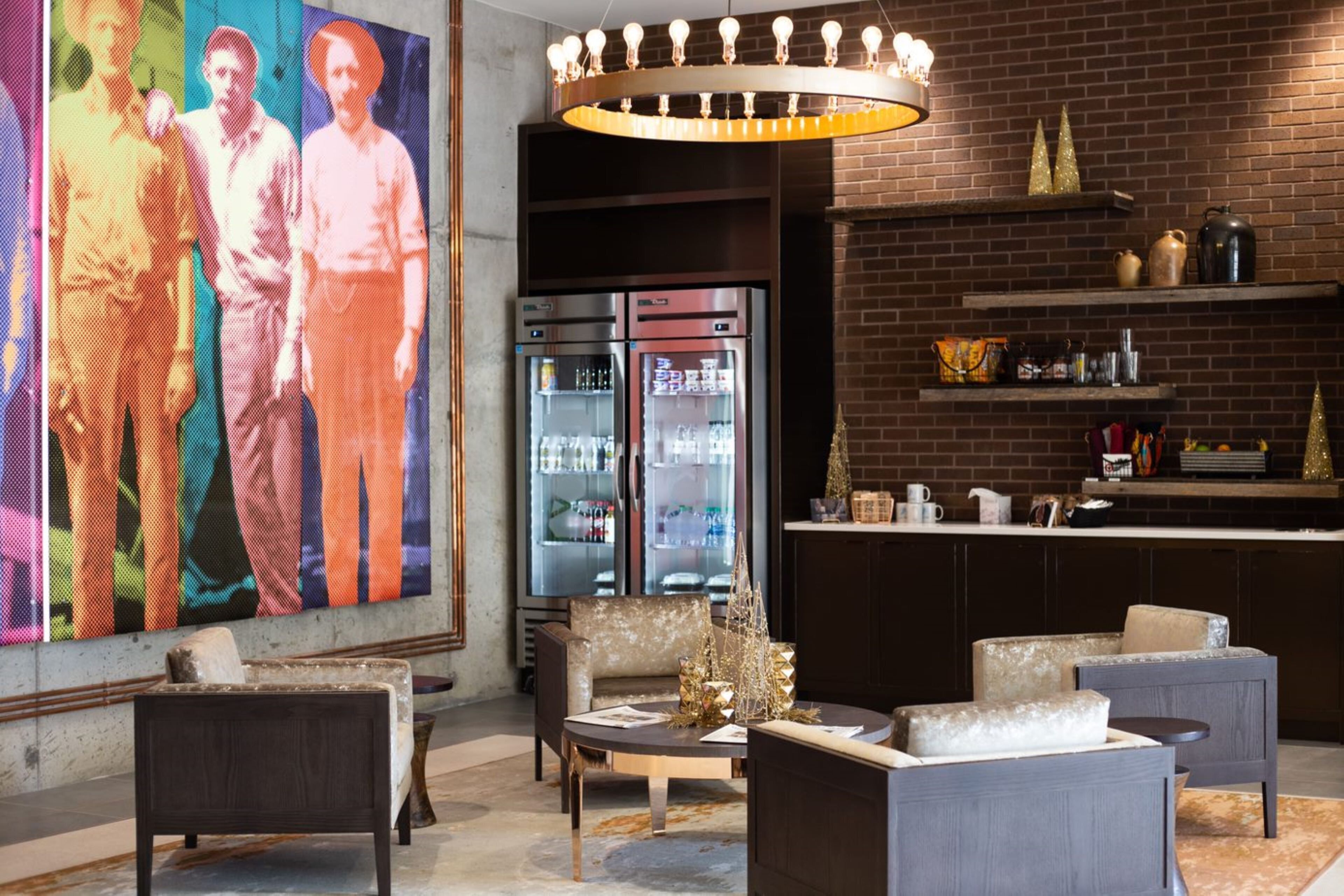 A modern lounge area with seating, a refrigerator, and a large digital art display.