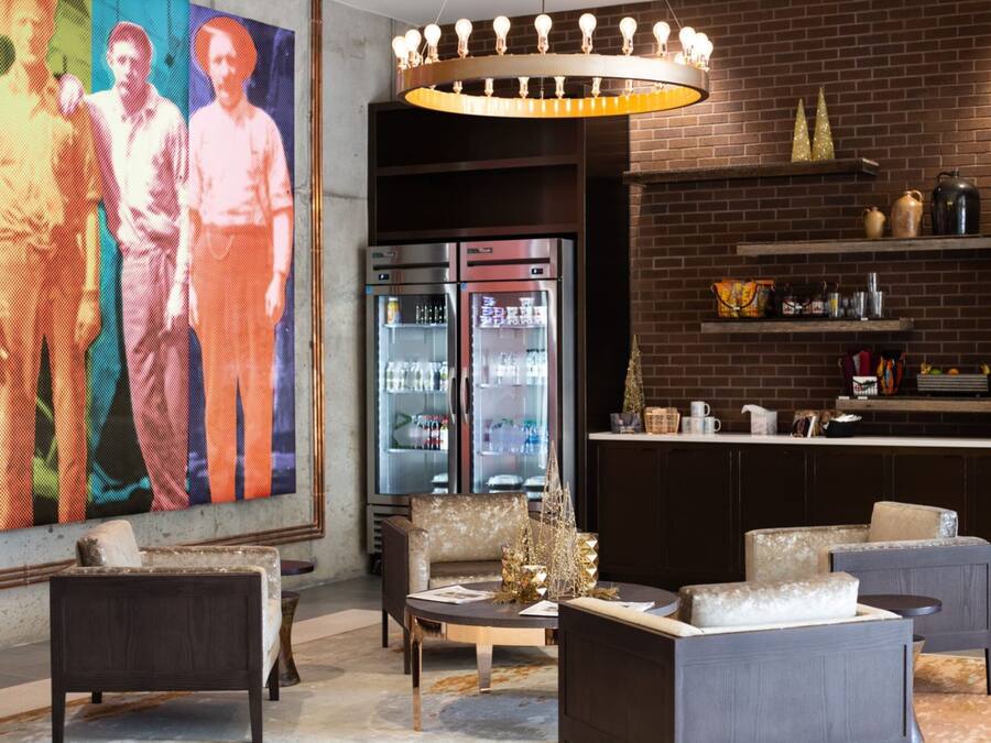 A modern lounge area with seating, a refrigerator, and a large digital art display.