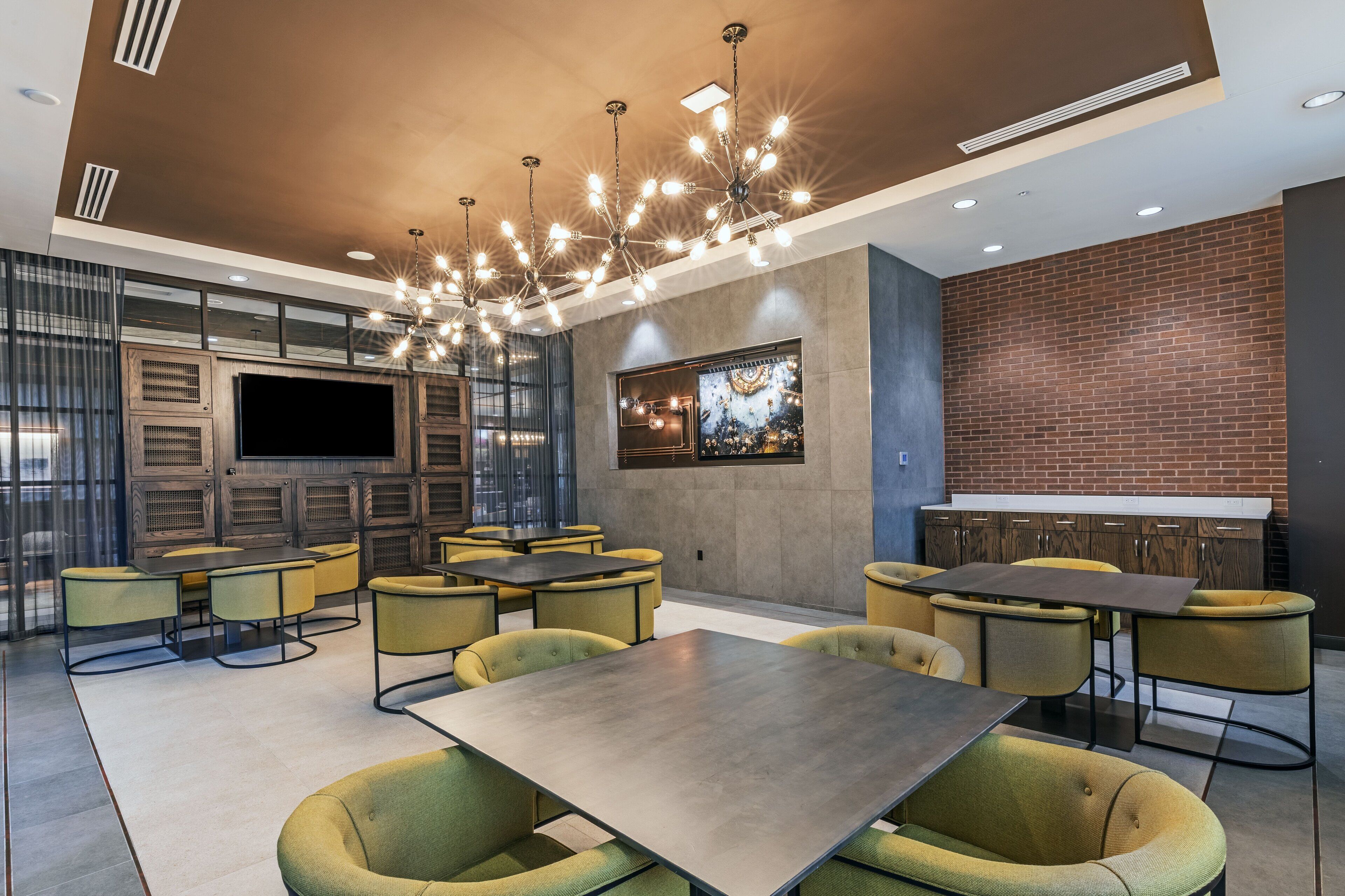 A modern lounge area with multiple seating options, a large flat-screen TV, and a decorative wall piece.