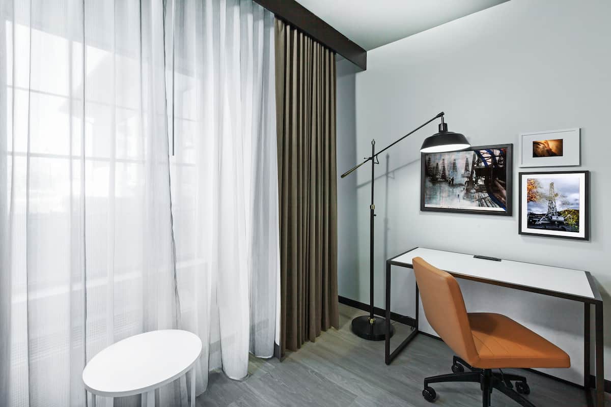 Un espace de bureau moderne comprenant un bureau, une chaise et une lampe sur pied.