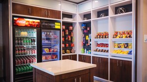 A well-stocked snack and beverage refrigerator with Coca-Cola and other drinks, a display of various snacks and chips, and a clean, organized layout. - Holiday Inn & Suites Houston NW - Vintage Park Area by IHG (Houston)