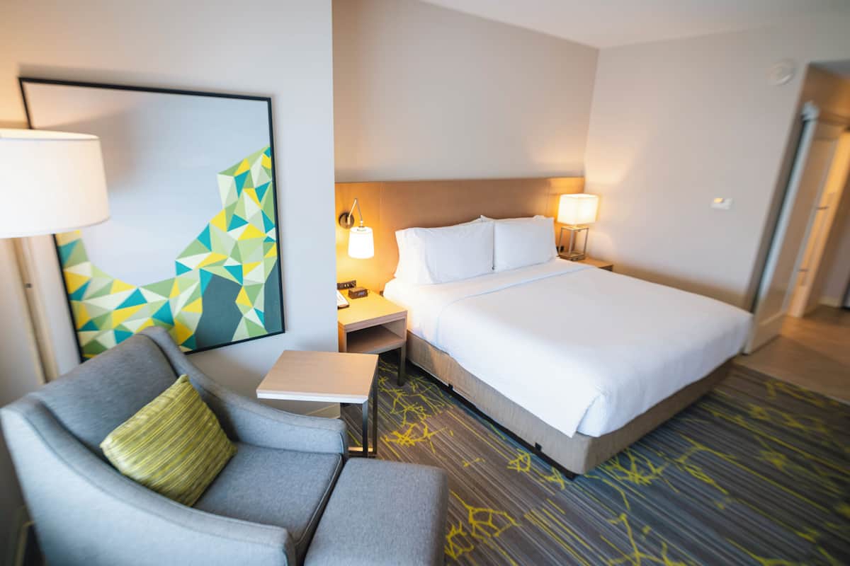 Une chambre d’hôtel avec un lit, un bureau, une chaise et un tableau au mur.