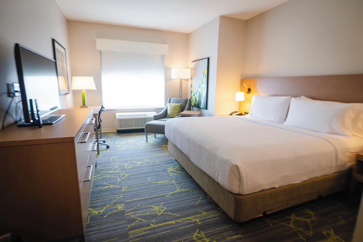 Une chambre d’hôtel avec un lit, un bureau, une chaise et une fenêtre donnant sur un paysage agréable.