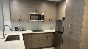 A modern kitchen with stainless steel appliances, a white countertop, and wooden cabinets. - Holiday Inn & Suites Houston NW - Vintage Park Area by IHG (Houston)