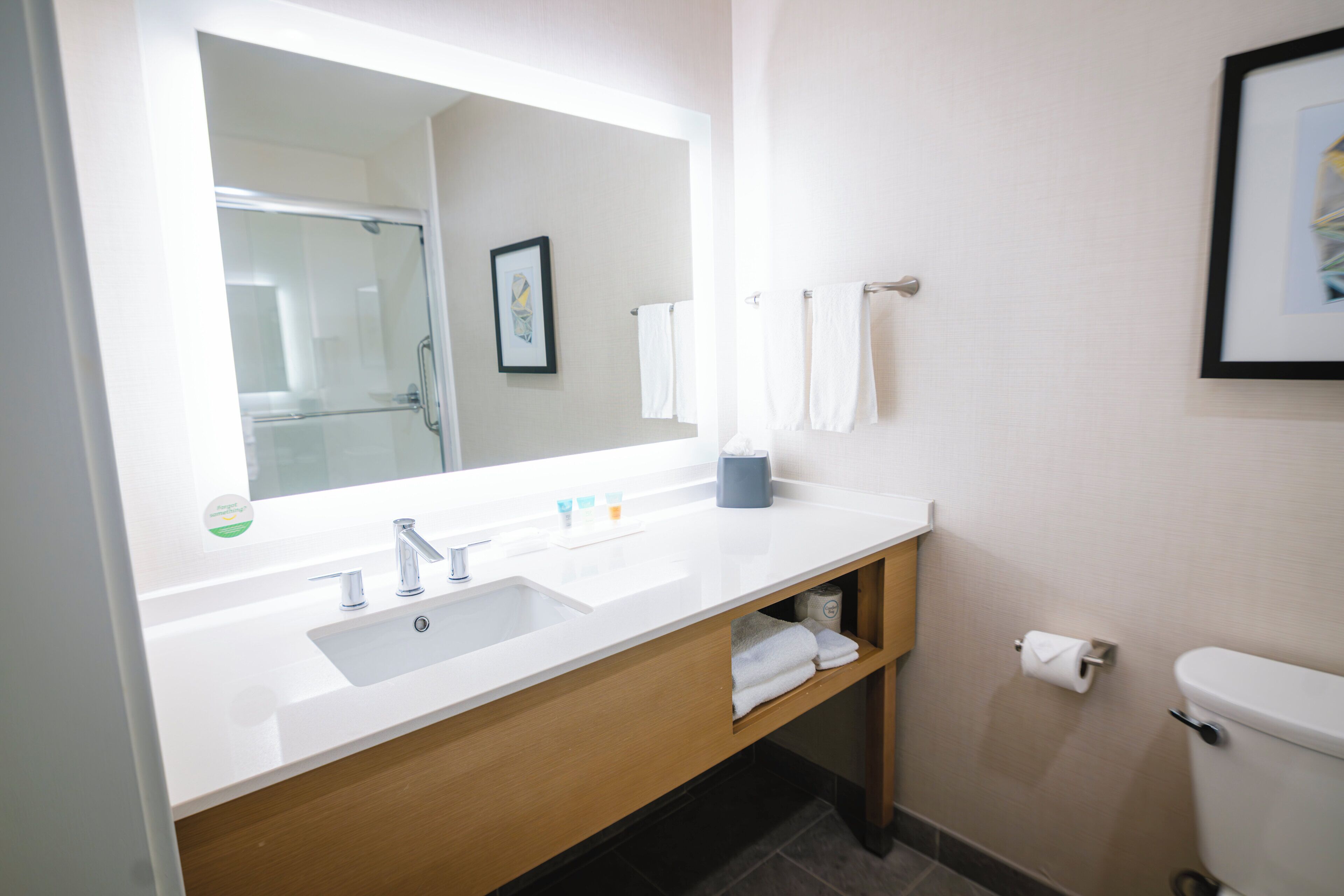 A bathroom with a white sink, a mirror, a towel rack, and a toilet.
