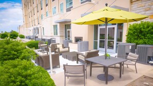 An outdoor patio with seating, a yellow umbrella, and a building in the background. - Holiday Inn & Suites Houston NW - Vintage Park Area by IHG (Houston)