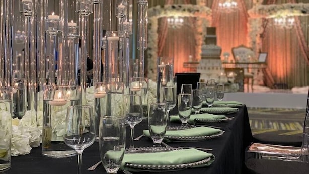A table set with clear glassware and candles, surrounded by white flowers and green napkins. - Holiday Inn & Suites Houston NW - Vintage Park Area by IHG (Houston)