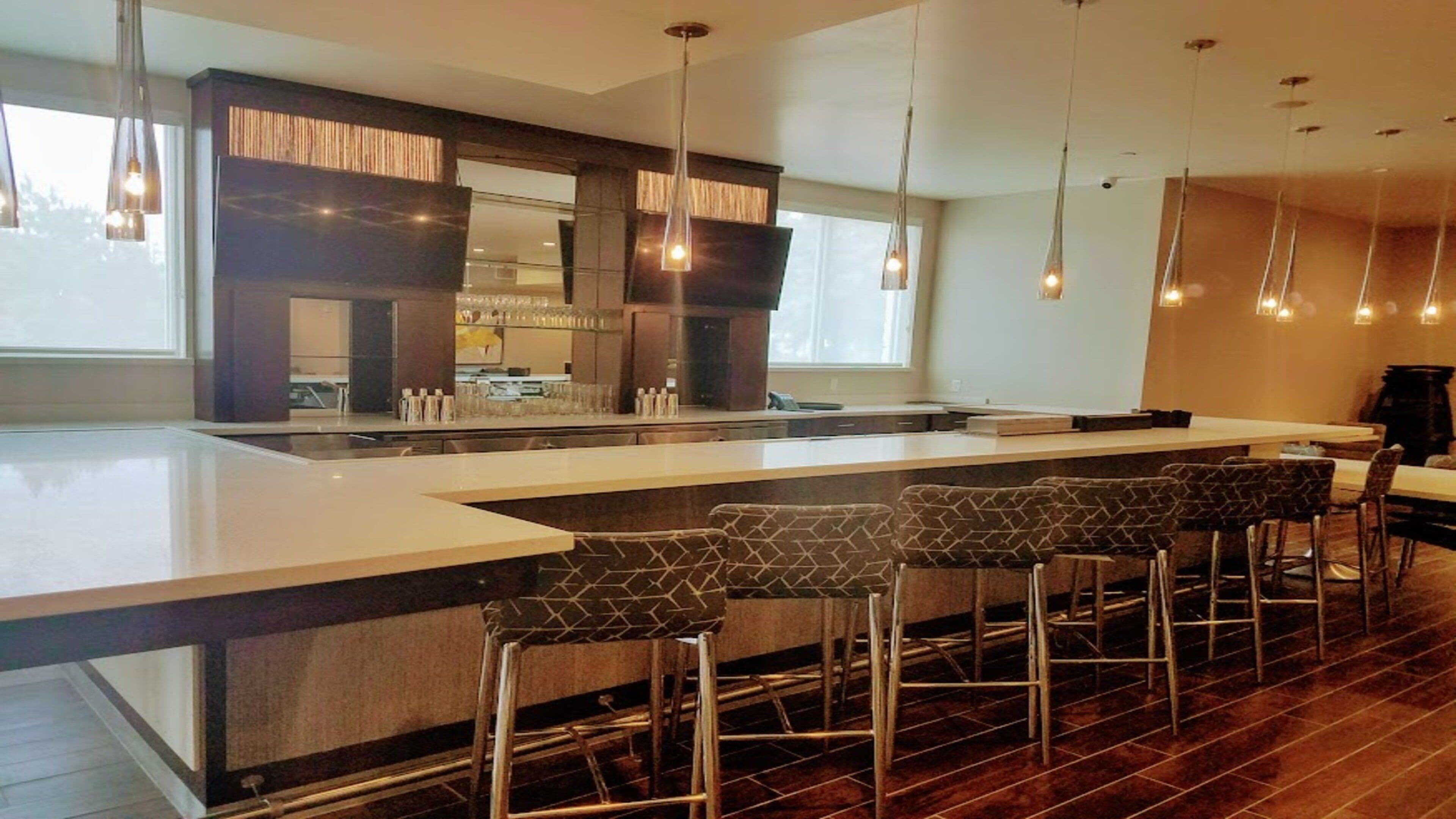 A modern kitchen with a large island, bar stools, pendant lighting, and a view of the outdoors.