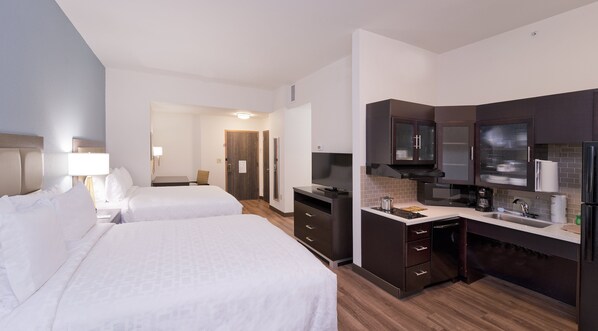 Hotelkamer met twee bedden, een bureau, een televisie, een magnetron en een kleine kitchenette.