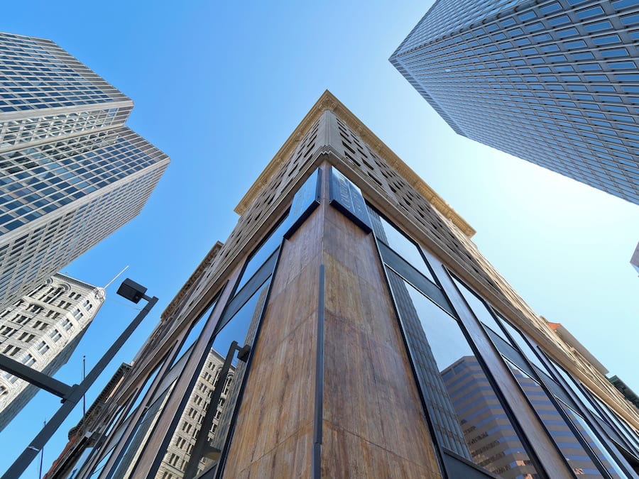 Un bâtiment moderne doté d’une façade en verre remarquable et d’un élément architectural classique sur sa partie supérieure.