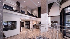 A multi-level hotel lobby with a wooden floor, glass railings, and a staircase.