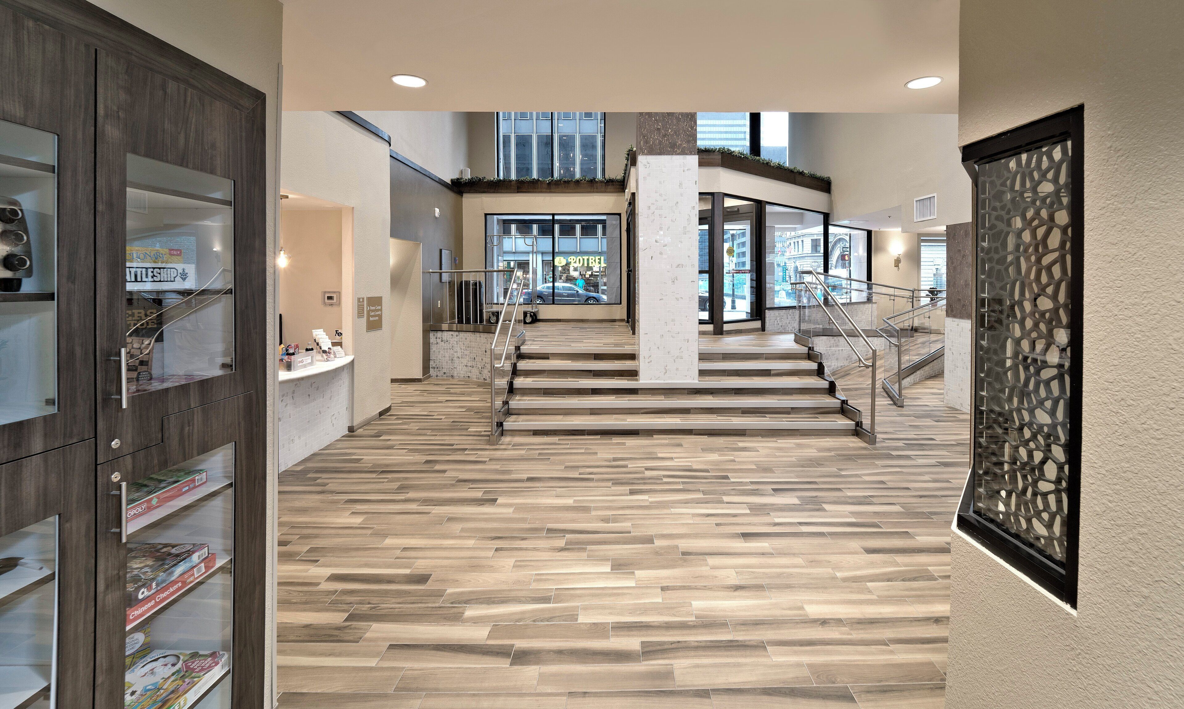 Un vestíbulo de hotel con piso de madera, un mostrador de recepción y una escalera que sube a un nivel superior.