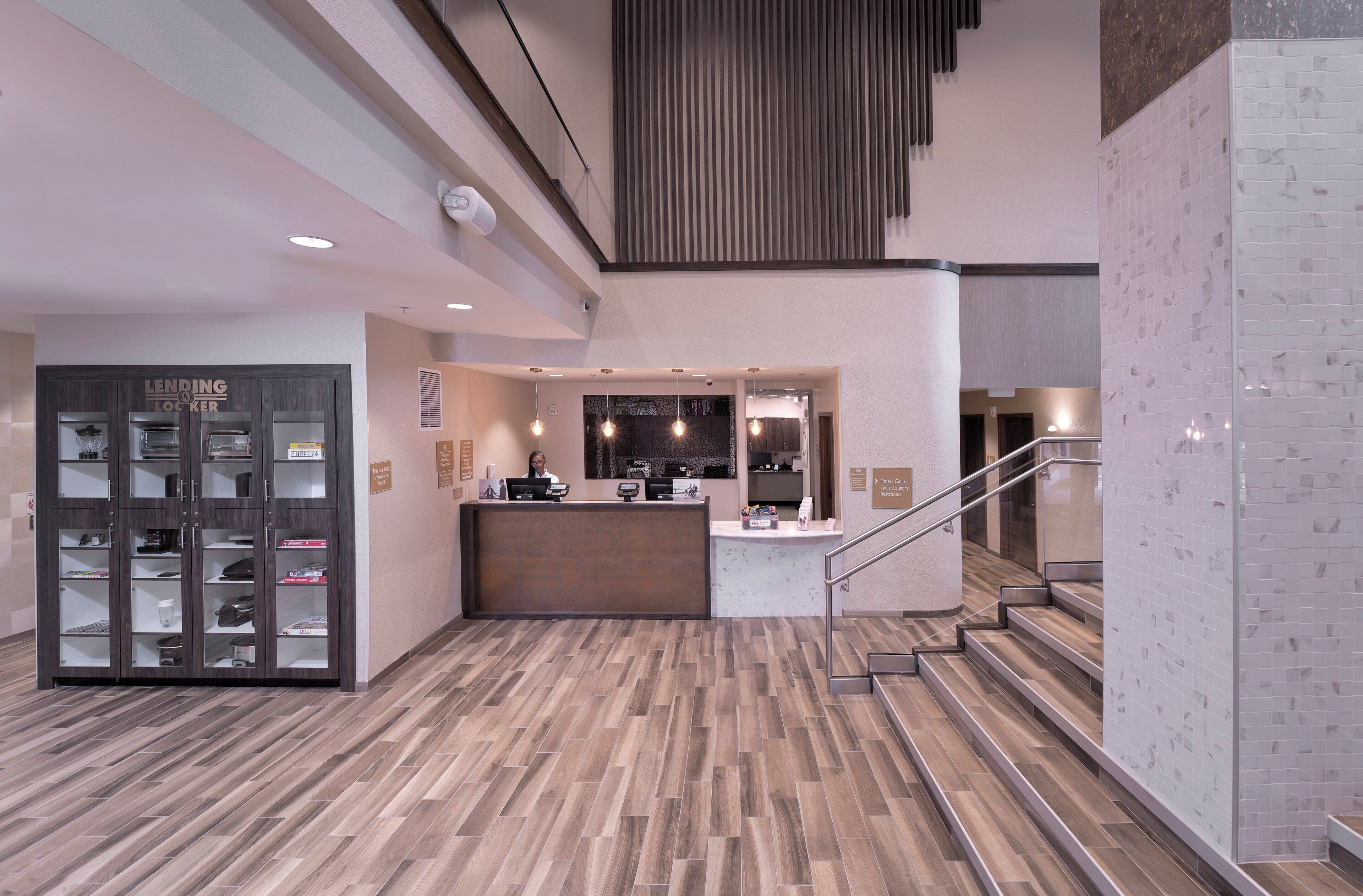 A hotel reception area with a counter, a staircase, and a lending locker.