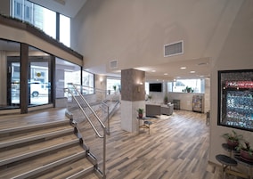 Un amplio vestíbulo de hotel con escalera, zona de estar y mostrador de recepción.