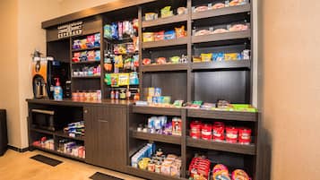 A self-service beverage station with a coffee machine, microwave, and various snacks and drinks.
