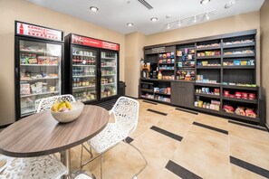 Eine Snackbar mit gekühlten Getränkeautomaten, einer Mikrowelle und Regalen voller Snacks und Gewürze.